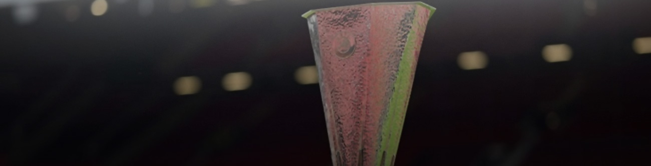 На изображении трофей футбольного турнира на затемнённом фоне со световыми бликами. Трофей имеет вытянутую форму с характерными узорами