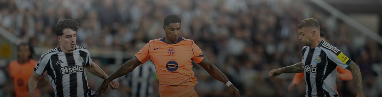 На изображении трое футболистов в момент игры. Игрок в оранжевой форме пытается пройти между двумя соперниками в черно-белой полосатой форме. На заднем плане видны размытие трибун и зрители